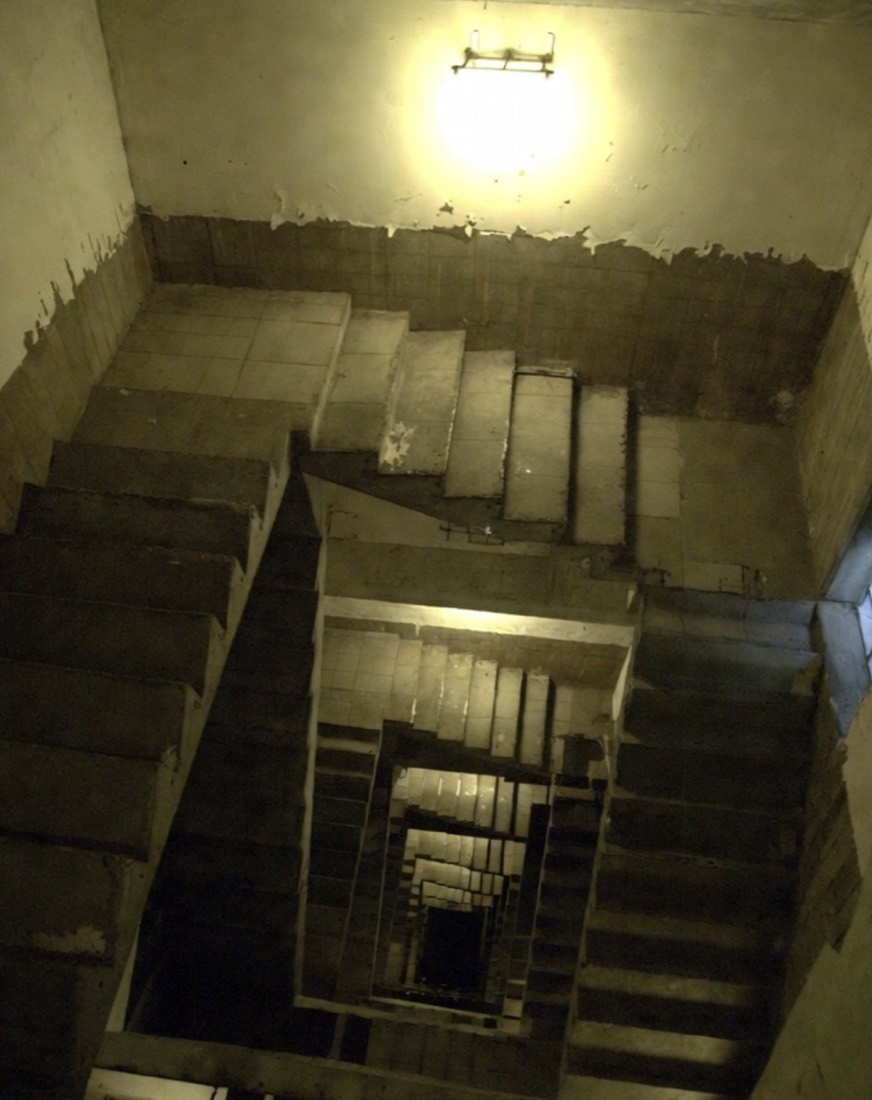a stairwell photographed from above, flights spiraling down into darkness